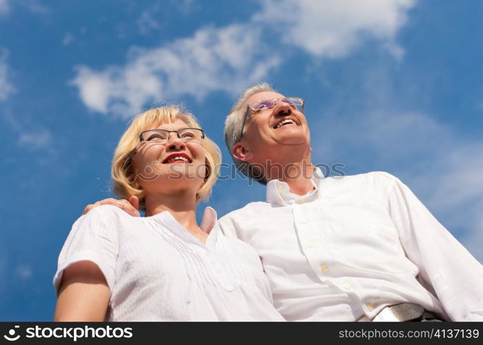 Happy mature couple - senior people (man and woman) already retired - looking to the blue sky in summer