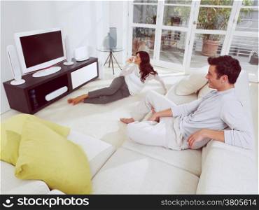 happy mature couple sitting on couch and watching television together