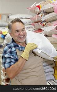 Happy mature salesperson carrying sack in feed store