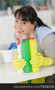 happy mature woman holding spray detergent