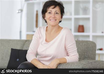 happy mature woman sitting on sofa