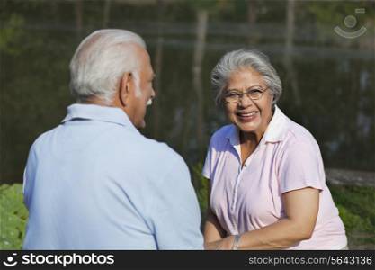 Happy mature woman smiling at park with man