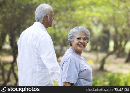 Happy mature woman smiling with man while walking in park