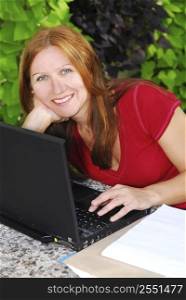 Happy mature woman working on portable computer at home, small business owner