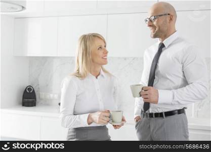 Happy mid adult business couple having coffee in kitchen
