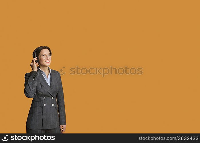 Happy mid adult woman standing while listening to music on headphones