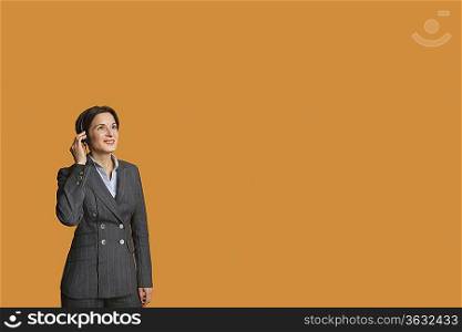 Happy mid adult woman standing while listening to music on headphones