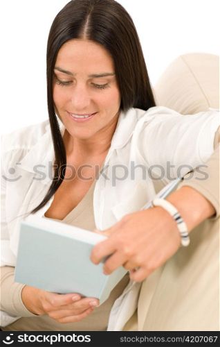 Happy mid-aged woman read book sitting on couch