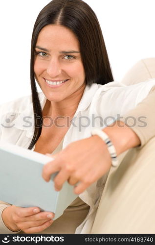Happy mid-aged woman with book sitting on couch