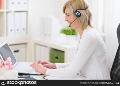 Happy middle age business woman with headset at work
