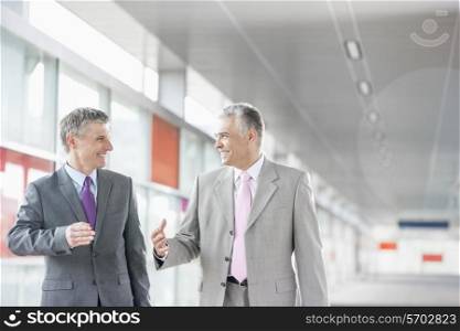 Happy middle aged businessmen talking while walking in railroad station