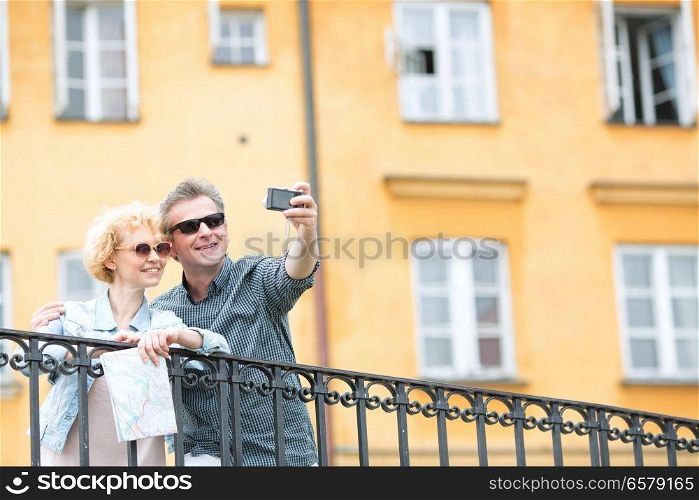 Happy middle-aged couple taking selfie through camera against building