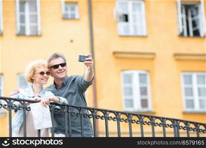Happy middle-aged couple taking selfie through camera against building