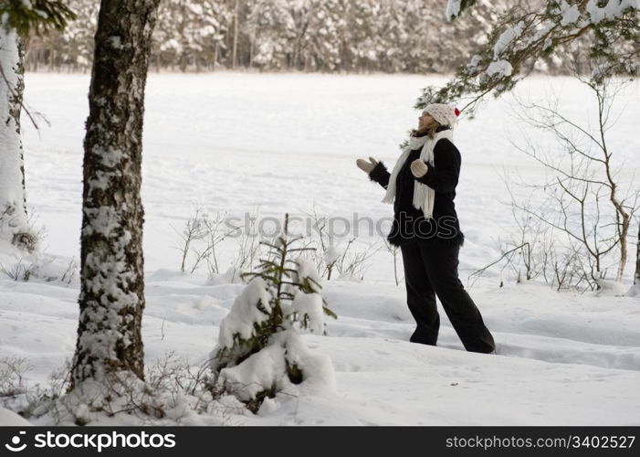 Happy middle-aged woman having fun on winters day in forest.