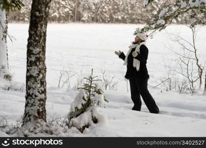 Happy middle-aged woman having fun on winters day in forest.