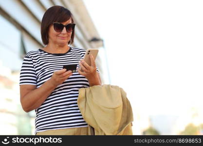 happy middle aged woman in sunglasses with smartphone and credit card outdoors. City on day background with copy space. Business people shopping via online application media concept. happy middle aged woman in sunglasses with smartphone and credit card outdoors. City on day background with copy space. Business people shopping via online application media concept.