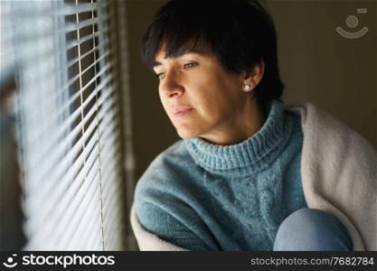 Happy middle-aged woman with nostalgic look as she gazes out the window. Female in her 50s. Happy middle-aged woman with nostalgic look as she gazes out the window.