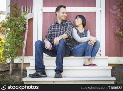 Happy Mixed Race Couple Relaxing on the Steps of Their Barn.