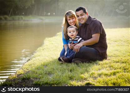 Happy Mixed Race Ethnic Family Posing for A Portrait in the Park by the Lake.