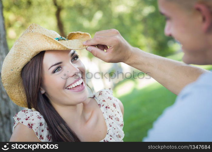 Happy Mixed Race Romantic Couple with Cowboy Hat Flirting in the Park.