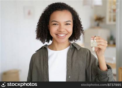 Happy mixed race teen girl tenant showing house key. Friendly smiling young biracial lady renter holding keys to new home apartment, standing in modern flat room. Rental service advertisement.. Keys to new home. Happy mixed race girl tenant shows house apartment key. Rental service advertising