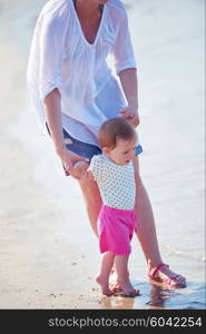 happy mom and baby on beach have fun while learning to walk and make first steps