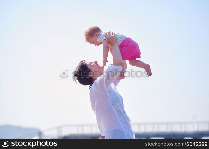 happy mom and baby on beach have fun while learning to walk and make first steps