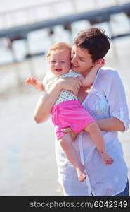 happy mom and baby on beach have fun while learning to walk and make first steps