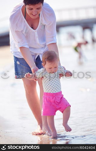 happy mom and baby on beach have fun while learning to walk and make first steps