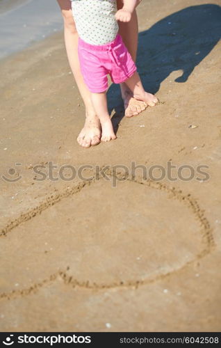 happy mom and baby on beach have fun while learning to walk and make first steps