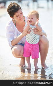 happy mom and baby on beach have fun while learning to walk and make first steps