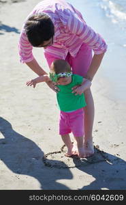 happy mom and baby on beach have fun while learning to walk and make first steps