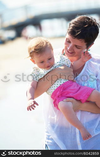 happy mom and baby on beach have fun while learning to walk and make first steps