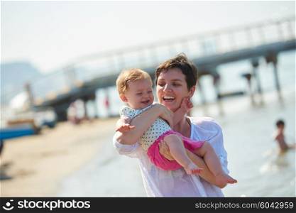 happy mom and baby on beach have fun while learning to walk and make first steps