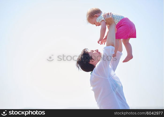 happy mom and baby on beach have fun while learning to walk and make first steps