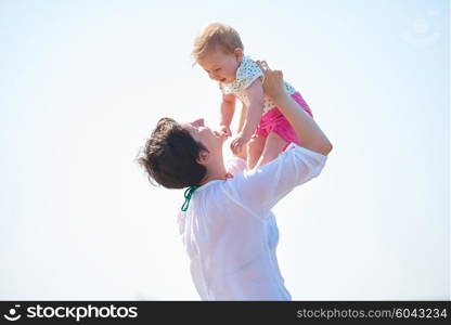 happy mom and baby on beach have fun while learning to walk and make first steps