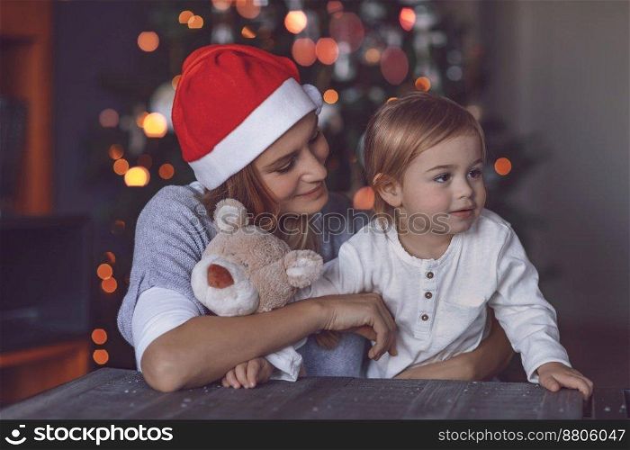 Happy Mom with Her Baby Boy Celebrating Christmas at Home. Receiving Gifts. Decorating Xmas Tree. Family Enjoying Winter Holidays.. Happy Family at Home on Christmas Eve