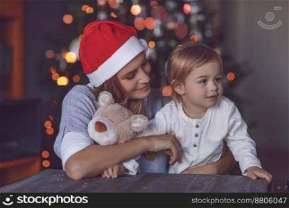 Happy Mom with Her Baby Boy Celebrating Christmas at Home. Receiving Gifts. Decorating Xmas Tree. Family Enjoying Winter Holidays.. Happy Family at Home on Christmas Eve