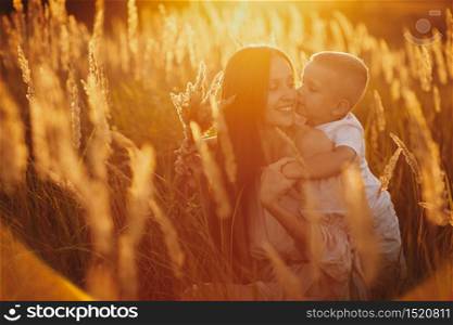 happy mom with son in the field at sunset. happy childhood. A young woman hugs her son.. happy mom with son in the field at sunset. happy childhood. A young woman hugs her son