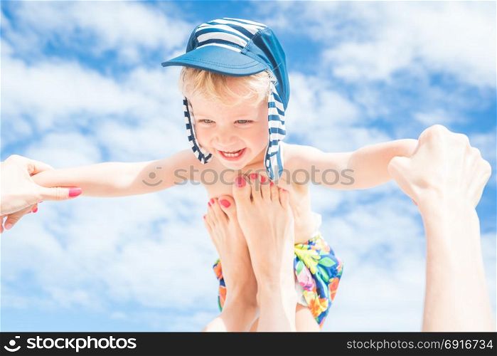 Happy moment,Mother throws up her smiling baby boy in the blue sky,summer time