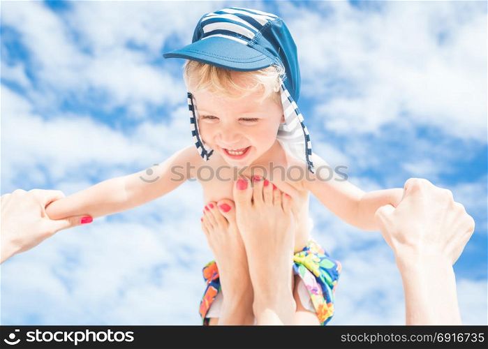 Happy moment,Mother throws up her smiling baby boy in the blue sky,summer time