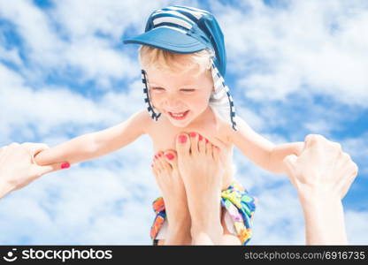 Happy moment,Mother throws up her smiling baby boy in the blue sky,summer time