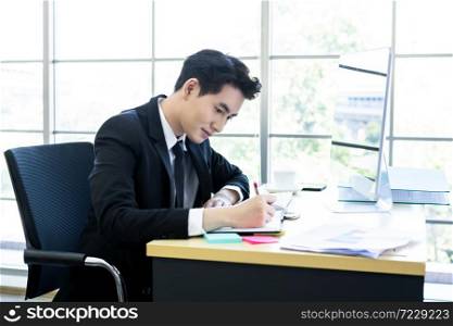 Happy mood a cheerful of asian young businessman have ideas make a note the successful business plan in document paper and computer on wooden table background in office.