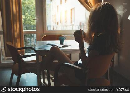 Happy morning - the girl is sitting in the kitchen and drinking the morning coffee