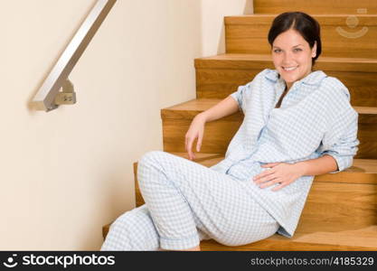 Happy morning young woman in pajamas sitting on the stairs