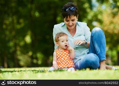 happy mother and baby child in park making first steps . Walking and hugging.