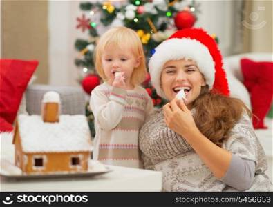 Happy mother and baby eating Christmas cookies