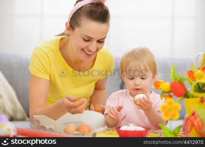 Happy mother and baby eating Easter eggs