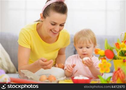 Happy mother and baby eating Easter eggs