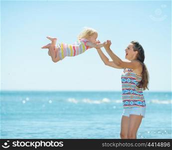Happy mother and baby girl playing at seaside